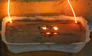 A composite of simulated lunar regolith and powdered aluminum heats up via wires as part of the fusion process that forms a brick. Eric J. Faierson