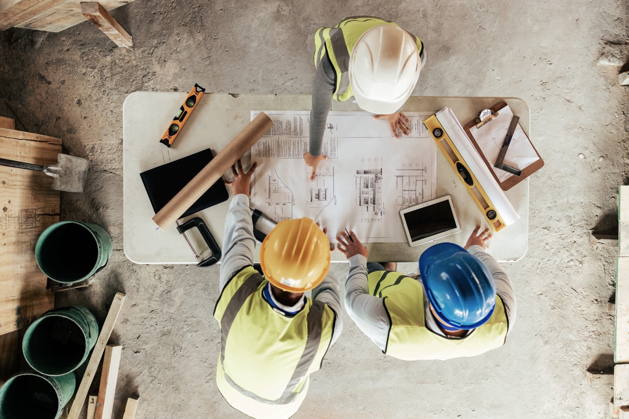Top view of construction workers looking at a blueprint and planning a project.