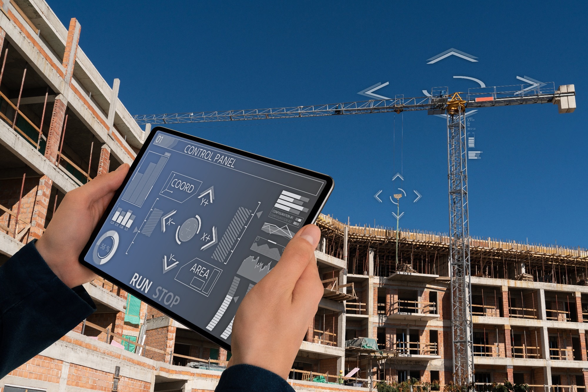 Builder with a digital tablet controls a remote-controlled unmanned crane.