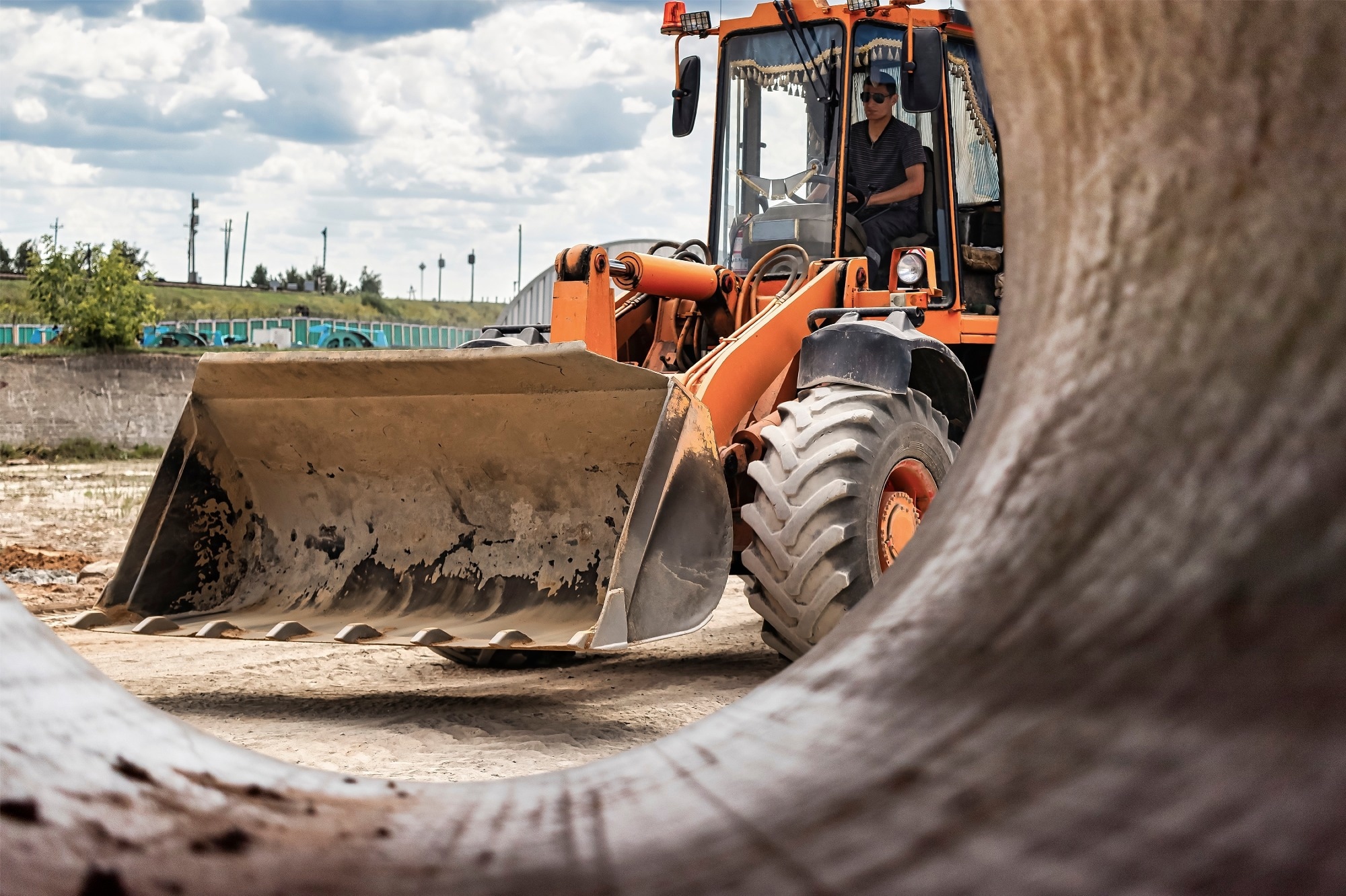 A large front loader pours sand into a pile at a construction site. Transportation of bulk materials. Construction equipment. Bulk cargo transportation.