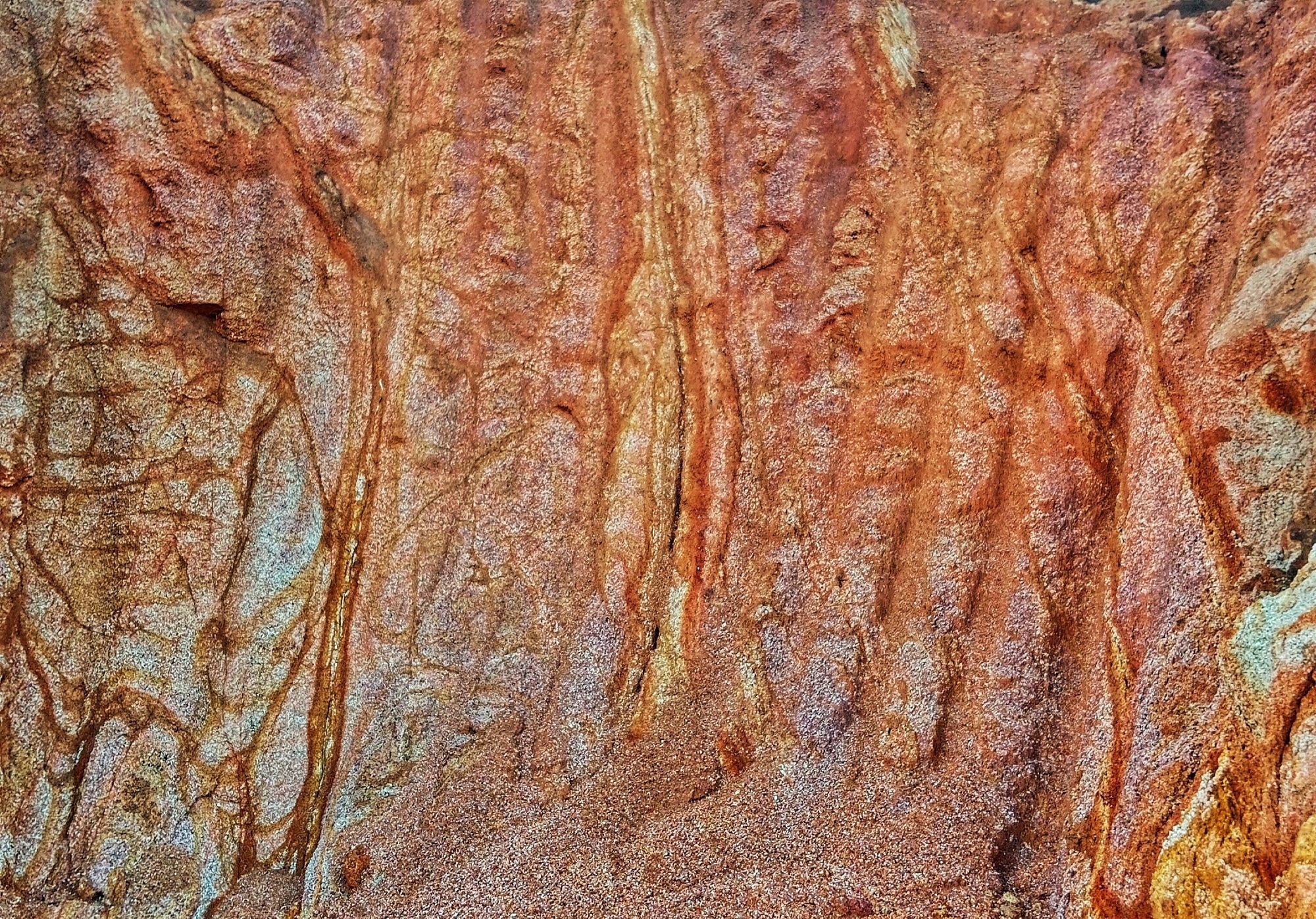 Natural abstract texture of eroded sandstone cliff with vertical water-carved patterns.