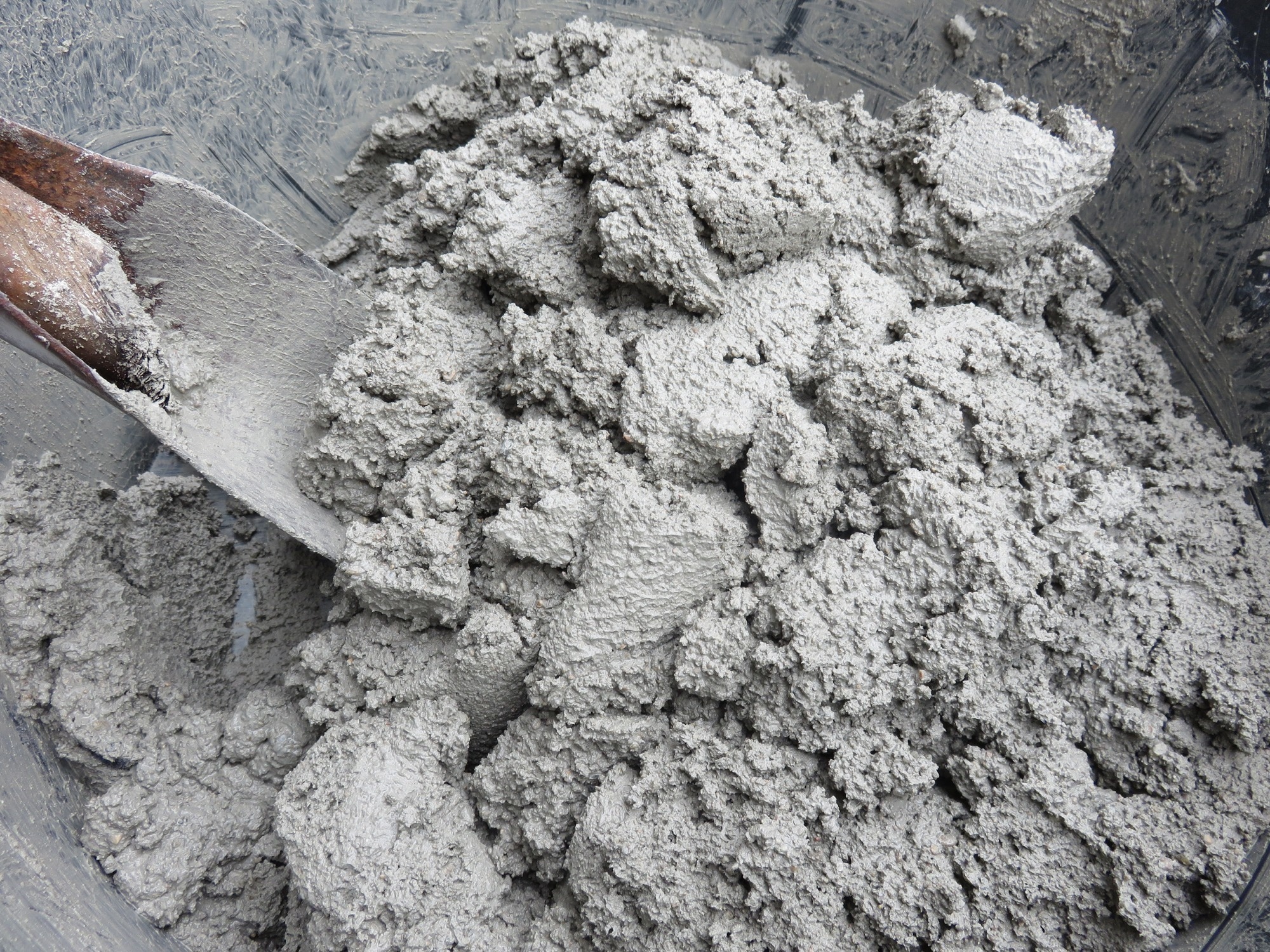 Mixing of sand, water, and Portland cement in powder form which is a basic ingredient of concrete