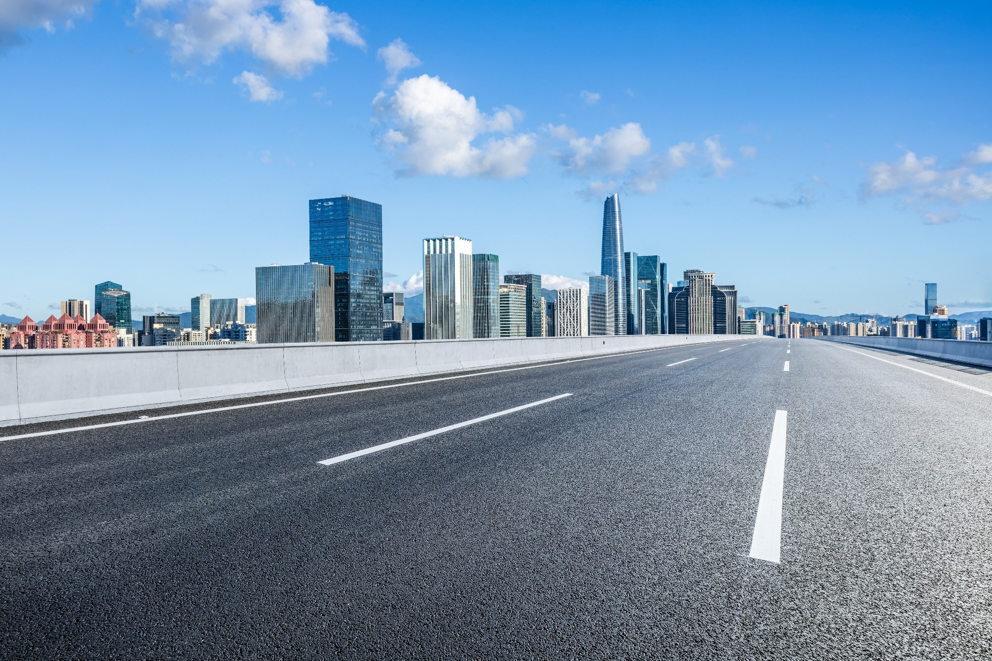 Asphalt highway road and city skyline with modern buildings.
