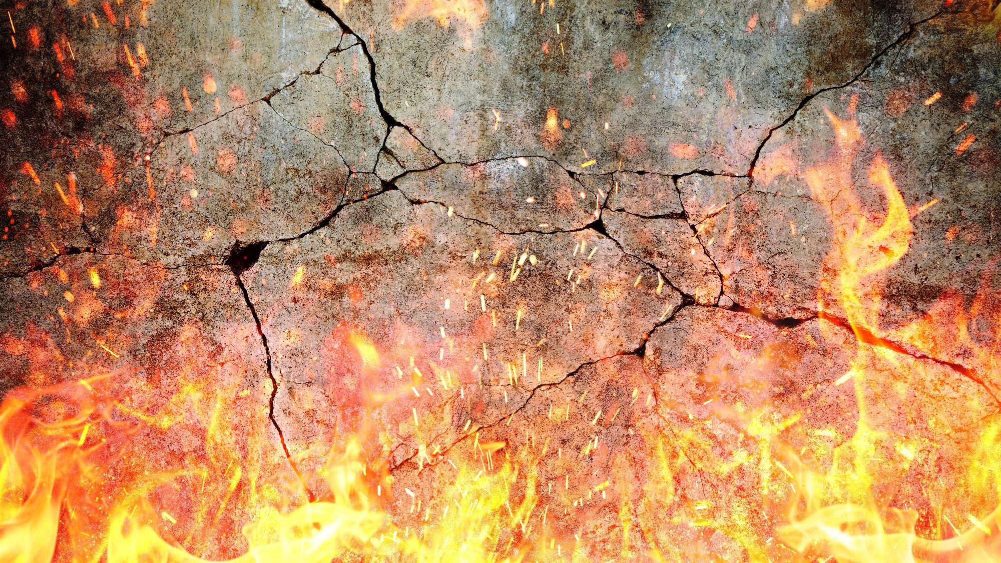 Flame of fire with sparks near grey d concrete damaged cracked wall.