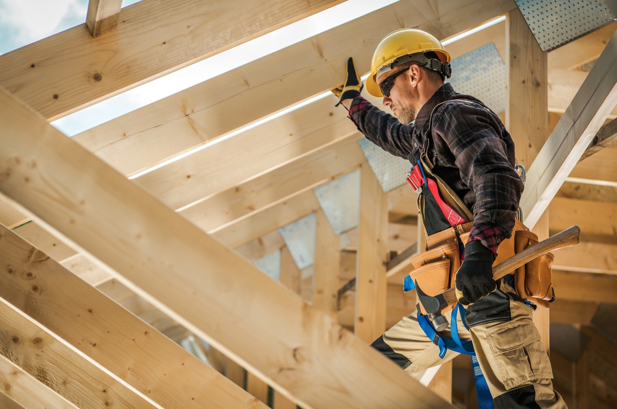 Construction worker on working on a wooden house frame.