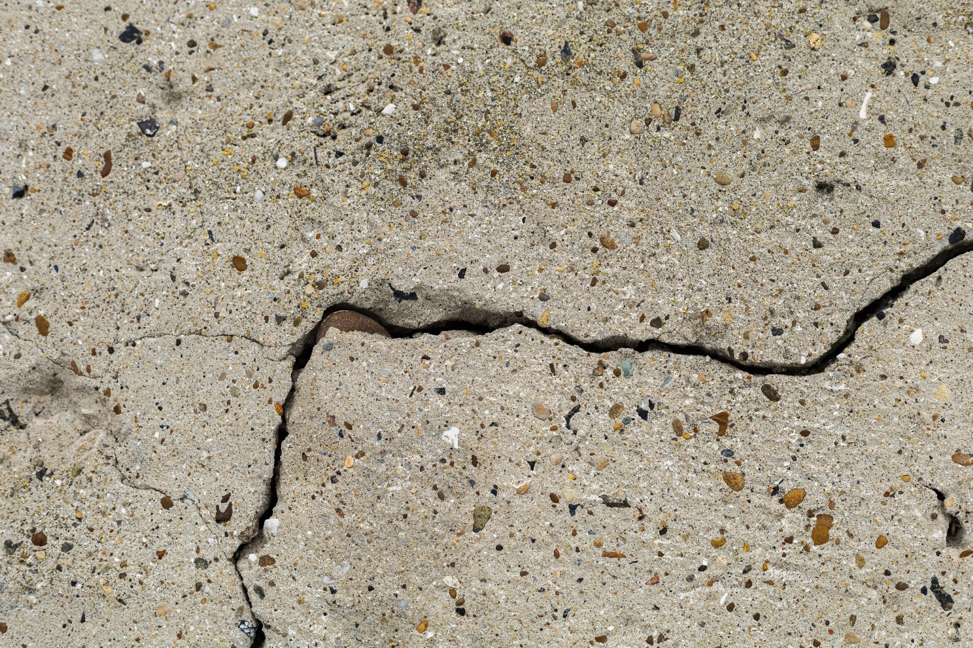 Rough textured surface of a cracked concrete foundation slab.