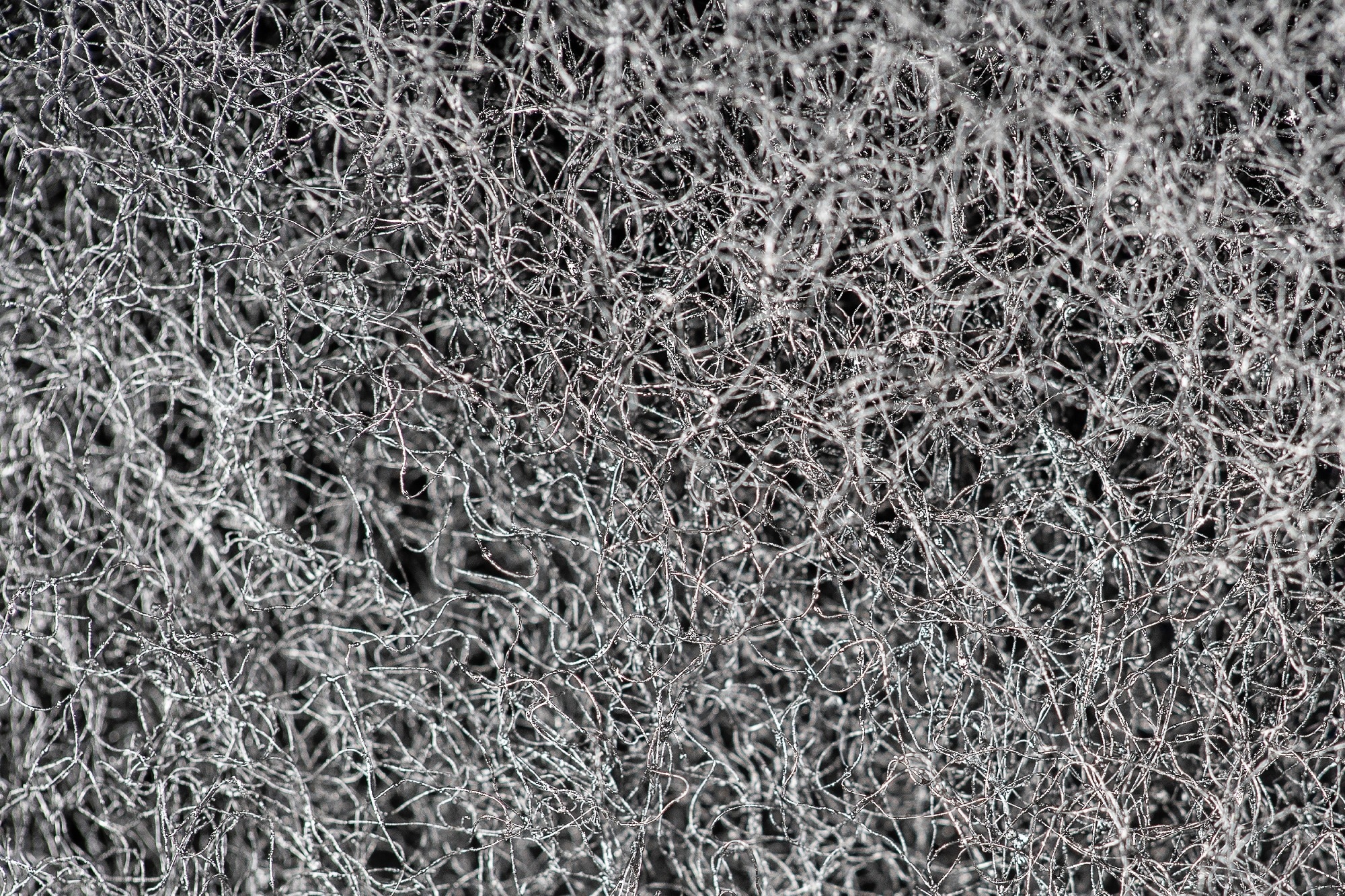 Dark abstract background and pattern of interwoven hairs, fibers and nanofibers.