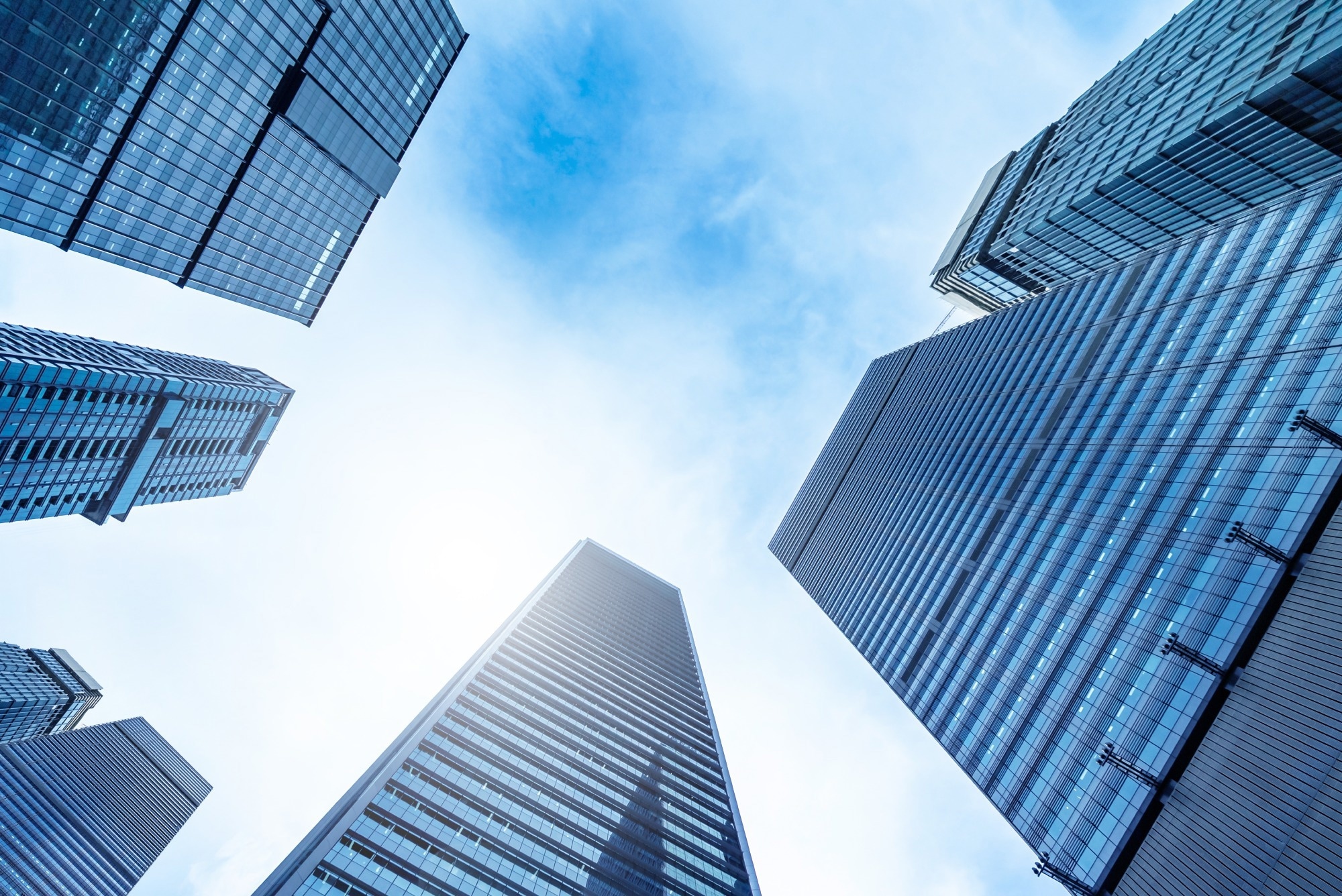 Low-angle view of modern glass skyscrapers with blue sky